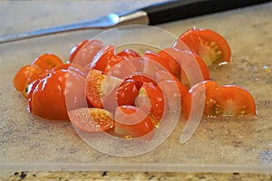 Shiny juicy cherry tomatoes cut into halves on counter