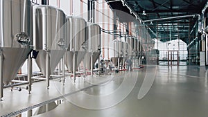 Shiny metal beer tanks at the modern brewery. Wide angle panoramic view, camera is moving