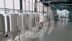 Shiny metal beer tanks at the modern brewery. Wide angle panoramic view, camera is moving