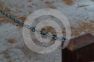 A shiny metal chain slides diagonally down to the right side of the frame. Abstract symbol of limiting the perspective