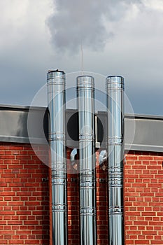 Shiny metal chimneys and vent pipes on a roof