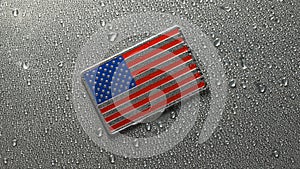 Shiny metal US American flag covered in water drops.