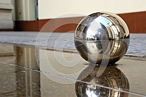 A shiny metallic sphere on a reflective surface