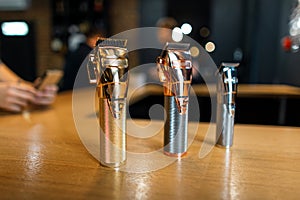 Shiny metallic vintage hair trimmers stand on a wooden table in a men`s hair salon. Male barbershop. photo