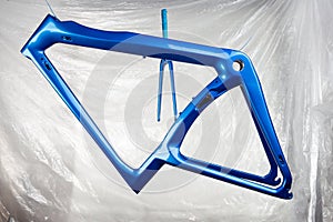 Shiny new fresh fresh paintwork coating paint of a metallic blue carbon racing road bicycle frame set with fork in front of paint photo