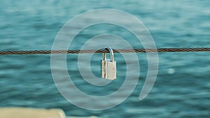 Shiny padlock hanging on a rope sea