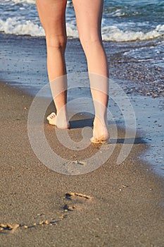 Shiny, perfect foots imprint in sand and woman foots on the beach in summer