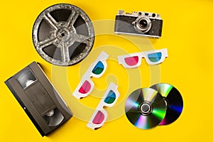 Shiny rainbow compact discs, filmstrip bobbin and retro camera. Black plastic VHS video cassette and cardboard 3D