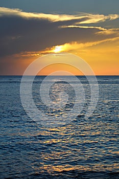 shiny sea over cloudy sky and sun during sunset in Cozumel, Mexico