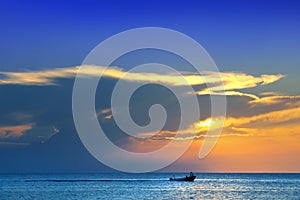 shiny sea and speedboat over cloudy sky and sun during sunset in Cozumel, Mexico