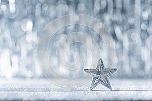 Shiny silver christmas star with defocused christmas lights in the background. Christmas background.