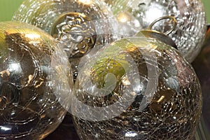 Shiny silver-colored orbs have reflections and are viewed close-up.