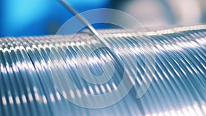 Shiny silver electrical wire unwinding from a spool