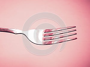 Shiny silver fork close-up in pink space