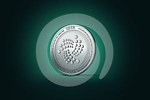Shiny silver IOTA coin on gently lit green blue background.