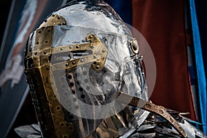 Shiny silver medieval iron knight helmet with a golden cross, full of scratches due to battles