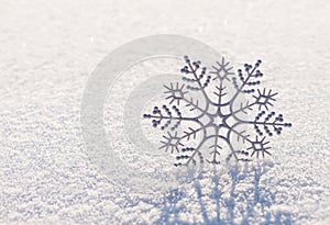 Shiny silver snowflake on brilliant snow, winter Christmas concept background