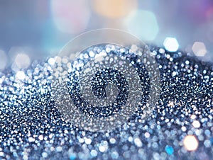 A shiny silver surface with a sequin texture and bokeh on the background.
