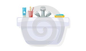 Shiny sink with toothpaste, two toothbrushes in red cup, blue soap in yellow box.