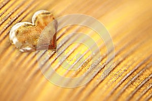 Shiny small golden heart on gold powder