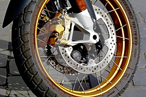 Shiny steel front brake disc detail on large motorcycle wheel