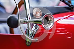 Shiny steel horn on red vintage car, closeup detail, only metal rim in focus