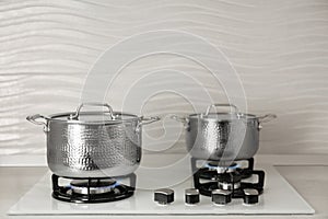 Shiny steel saucepans on modern gas stove