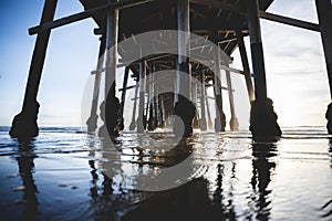 Shiny sun under the pier over reflecting water at Newport Beach, California