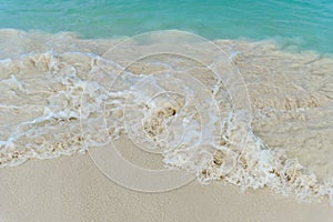 Shiny tropic sea wave on golden beach sand in Aruba