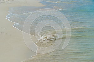 Shiny tropic sea wave on golden beach sand in Aruba