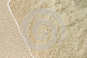 Shiny tropic sea wave on golden beach sand in Aruba