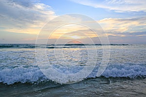 Shiny tropic sea wave on golden beach sand in sunset light