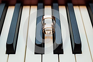 Shiny wedding golden rings on black and white keys of piano