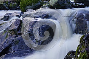 Shiny wet rocks in rapidly flowing small river