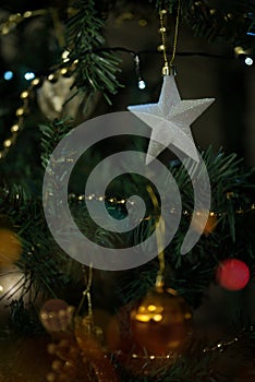 Shiny white star hanging on a decorated christmas tree. Close up.