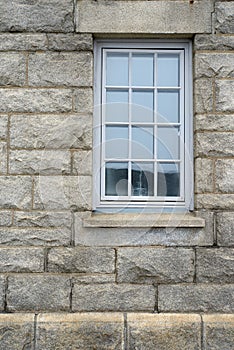 Shiny window and architecture of a grey brick wall. Exterior texture details of an old rustic residential building or