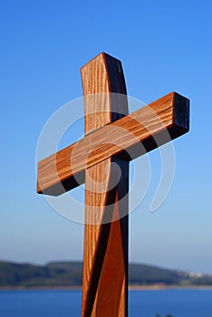 Shiny wooden cross in blue sky Easter symbol