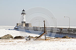 Ship anchor on shore along pier with lighthouse in Duluth, Minnesota