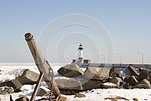 Ship anchor on rocky shore along pier with lighthouse in Duluth, Minnesota