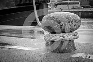 Ship is attached with a thick rope to a bollard in the harbour