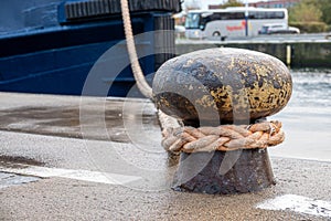 Ship is attached with a thick rope to a bollard in the harbour