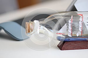 Ship in a bottle and laptop on the table. Dream of the next sea voyage. A business challenge in a wide world. Geography and techno