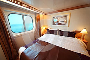 Ship cabin with bed and window with view on sea