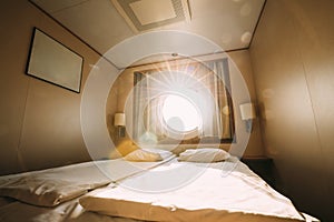 Ship Cabin With Bed And Window With View On Sea. Luxury Cabin On Ferry Boat Or Cruise Liner. Sunset Sun Shine Through