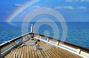 Ship in a calm sea. Rainbow on the horizon.