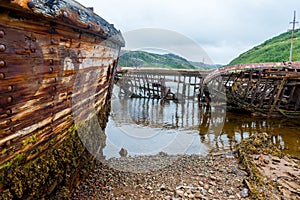 Ship cemetery in Teriberka on the coast of the Barents Sea. Old broken fishing boats in the water on the shore.