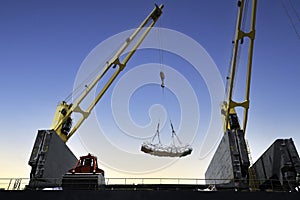 Ship crane lift jumbo sling of sugar bags load into ship hold. Bag cargo loading to ship for export.
