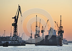 Ship in dry-dock and cranes at sunset