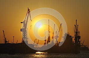 Ship in dry dock and cranes at sunset