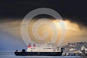 Ship ferry landing arrival at dock port under black storm clouds in the sky Wemyss Bay Scotland photo